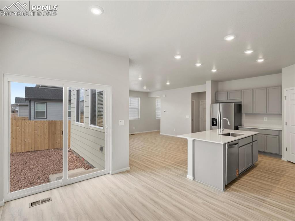 Image 11 of 30: Kitchen with recessed lighting, open floor plan, an island with sink, light
