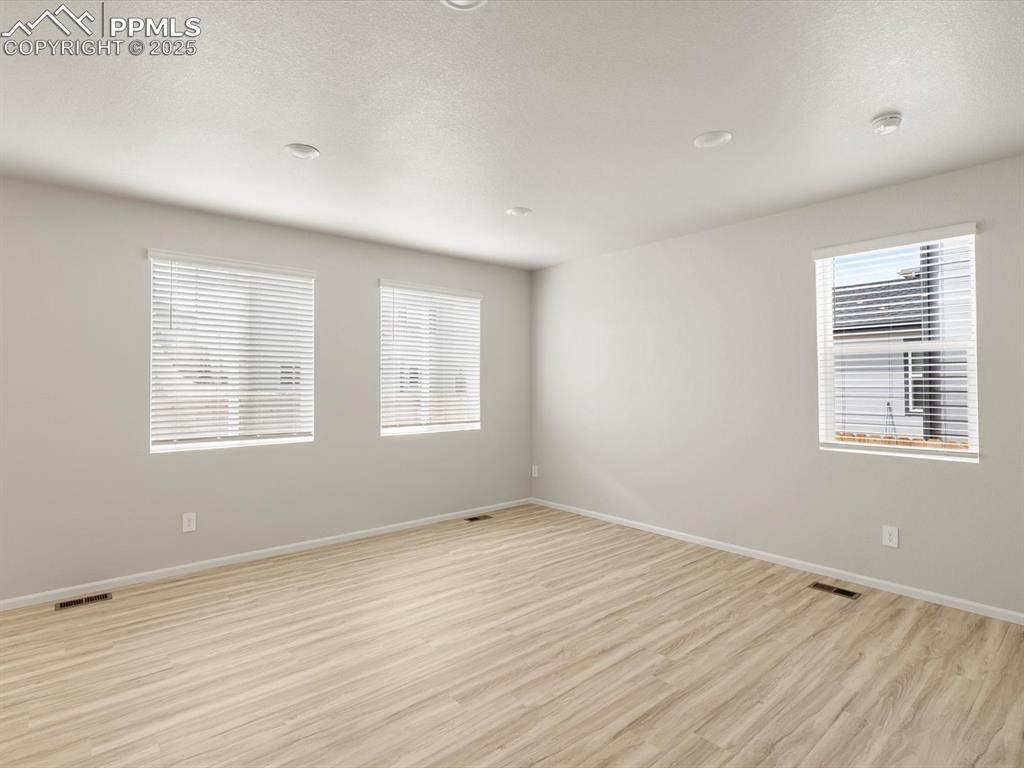 Image 13 of 30: Spare room featuring light wood finished floors, a textured ceiling, and re
