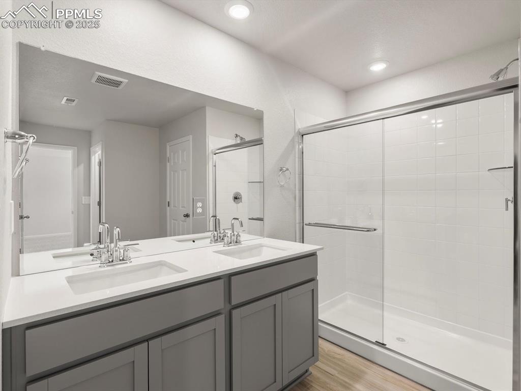 Image 27 of 30: Full bathroom with a stall shower, double vanity, and light wood-type floor