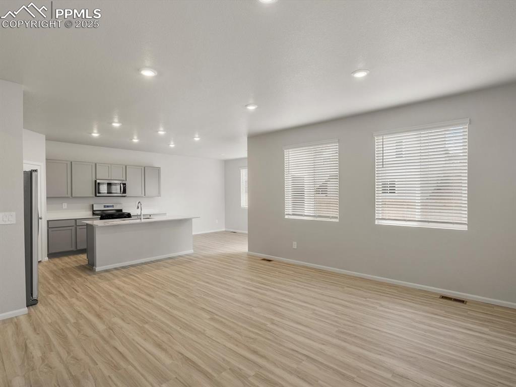 Image 4 of 30: Kitchen featuring gray cabinetry, light wood-type flooring, open floor plan