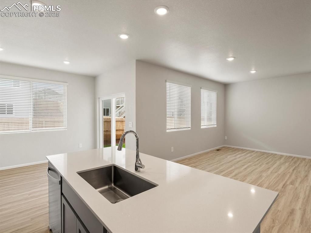 Image 9 of 30: Kitchen with light wood-type flooring, a kitchen island with sink, recessed