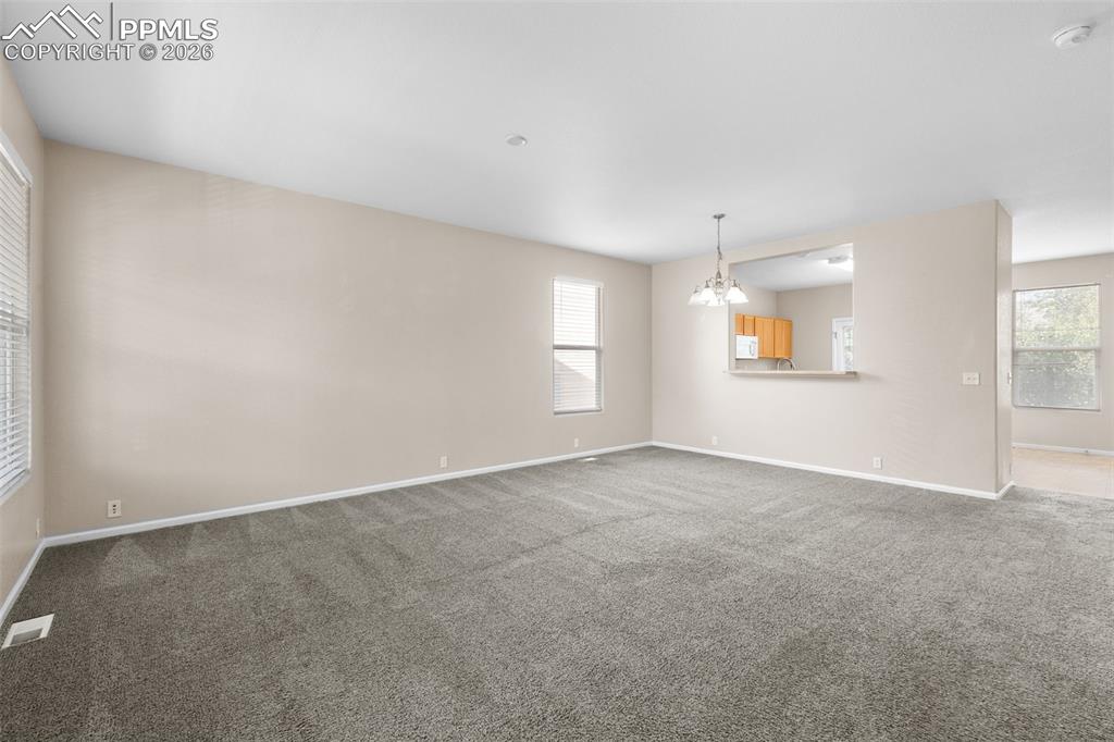 Image 13 of 38: Unfurnished living room featuring carpet and a chandelier