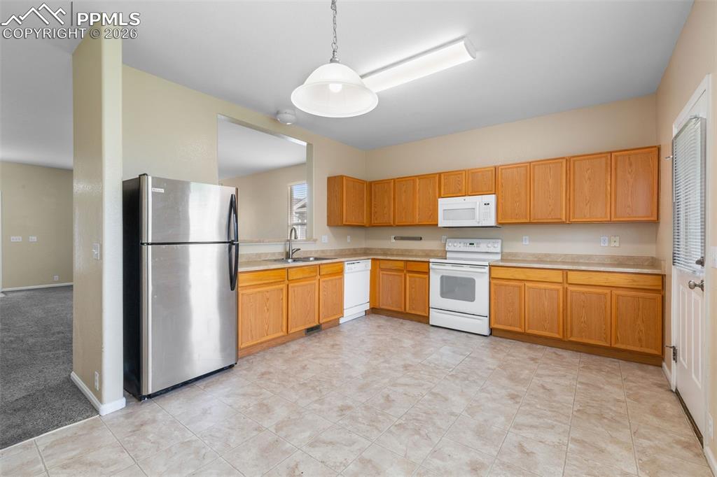Image 15 of 38: Unfurnished Kitchen with white appliances, light countertops, and hanging l