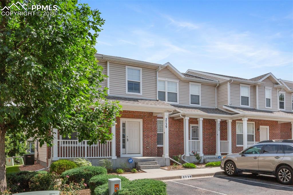 Image 2 of 38: View of front of house with uncovered parking, a porch, brick siding, and a