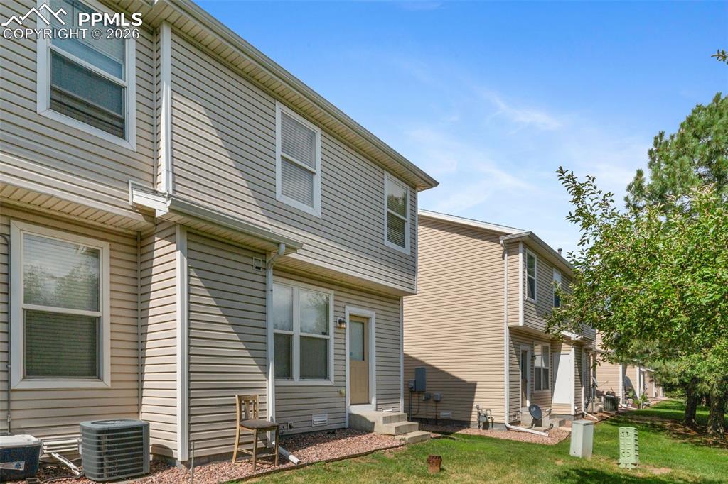 Image 32 of 38: Rear view of house featuring entry steps and a lawn