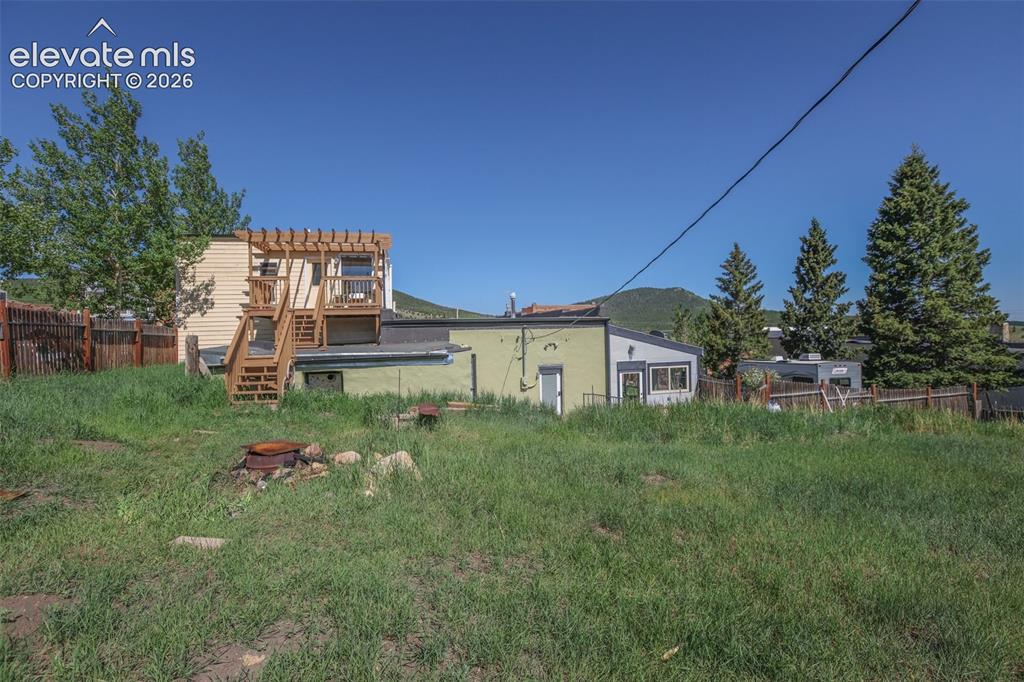 Image 4 of 43: from the yard, looking east, stairs lead to deck off of the bedroom/bath ov