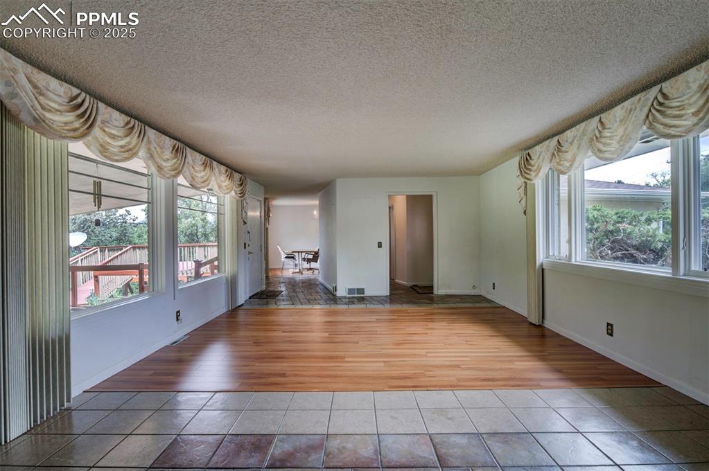 Image 10 of 49: Unfurnished living room featuring light tile patterned floors, a textured c