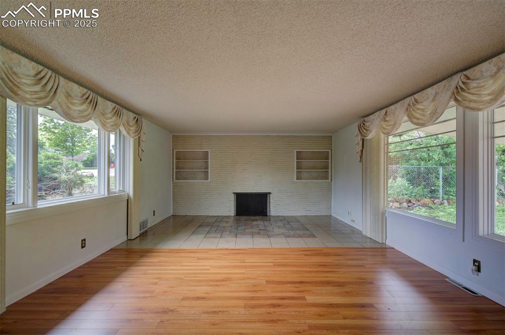 Image 11 of 49: Unfurnished living room featuring a textured ceiling, wood finished floors,
