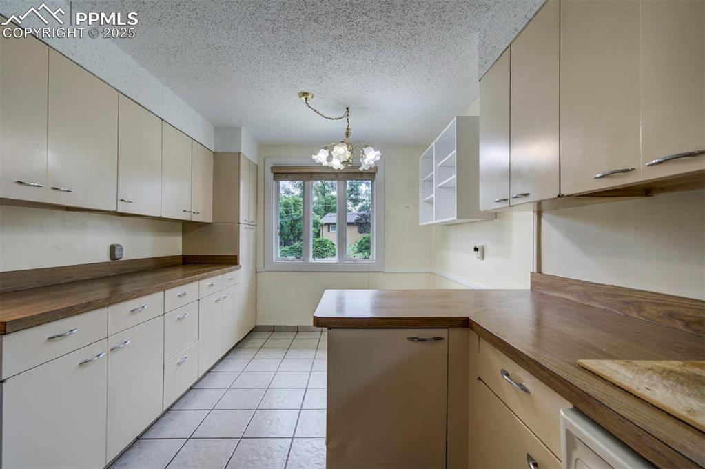 Image 12 of 49: Kitchen with wood counters, a chandelier, light tile patterned flooring, a