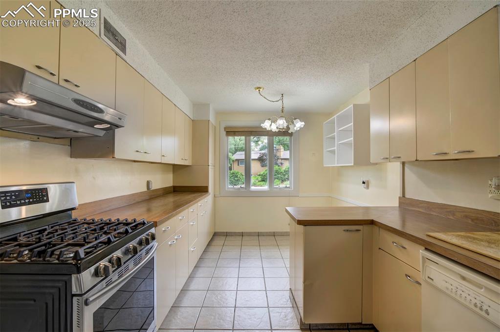 Image 15 of 49: Kitchen with stainless steel range with gas cooktop, under cabinet range ho