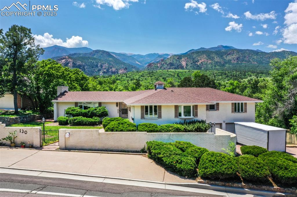 Image 2 of 49: Single story home with a fenced front yard, a gate, a mountain view, an att
