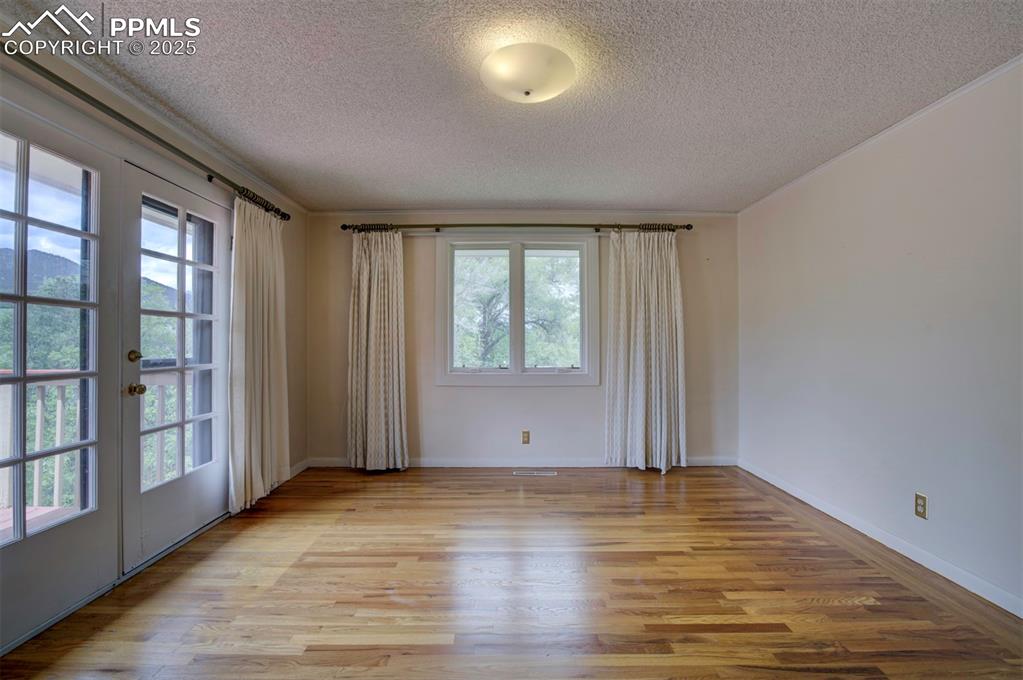 Image 20 of 49: Spare room featuring a textured ceiling, wood finished floors, french doors