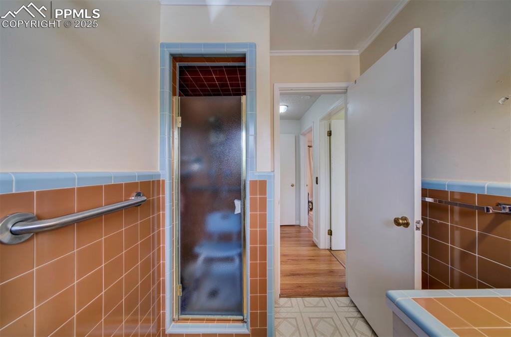 Image 24 of 49: Bathroom with tile walls, ornamental molding, and a wainscoted wall