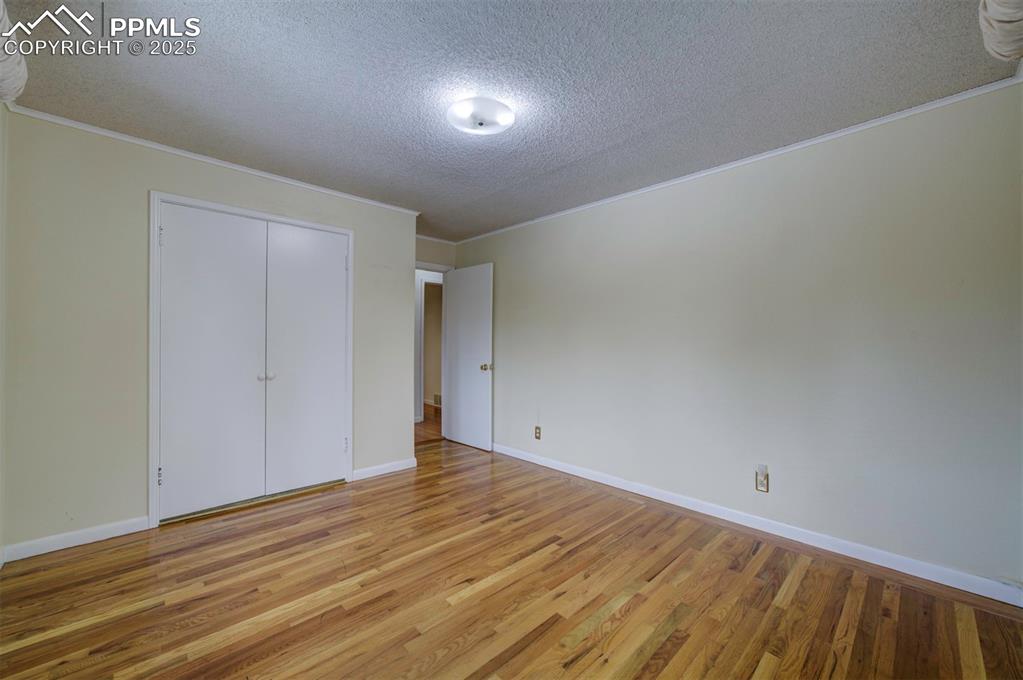 Image 26 of 49: Unfurnished bedroom featuring a textured ceiling, wood finished floors, orn
