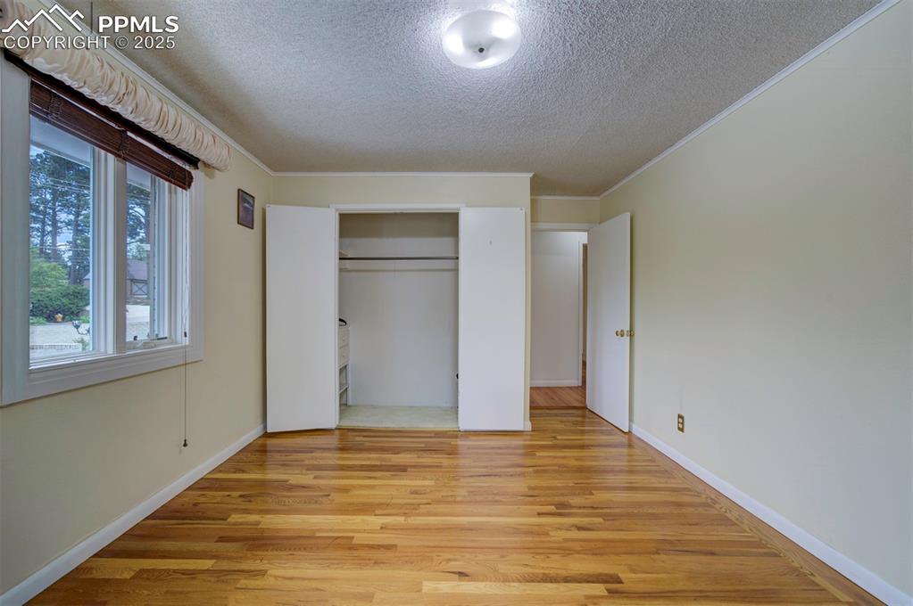 Image 27 of 49: Unfurnished bedroom with a textured ceiling, light wood-style flooring, cro
