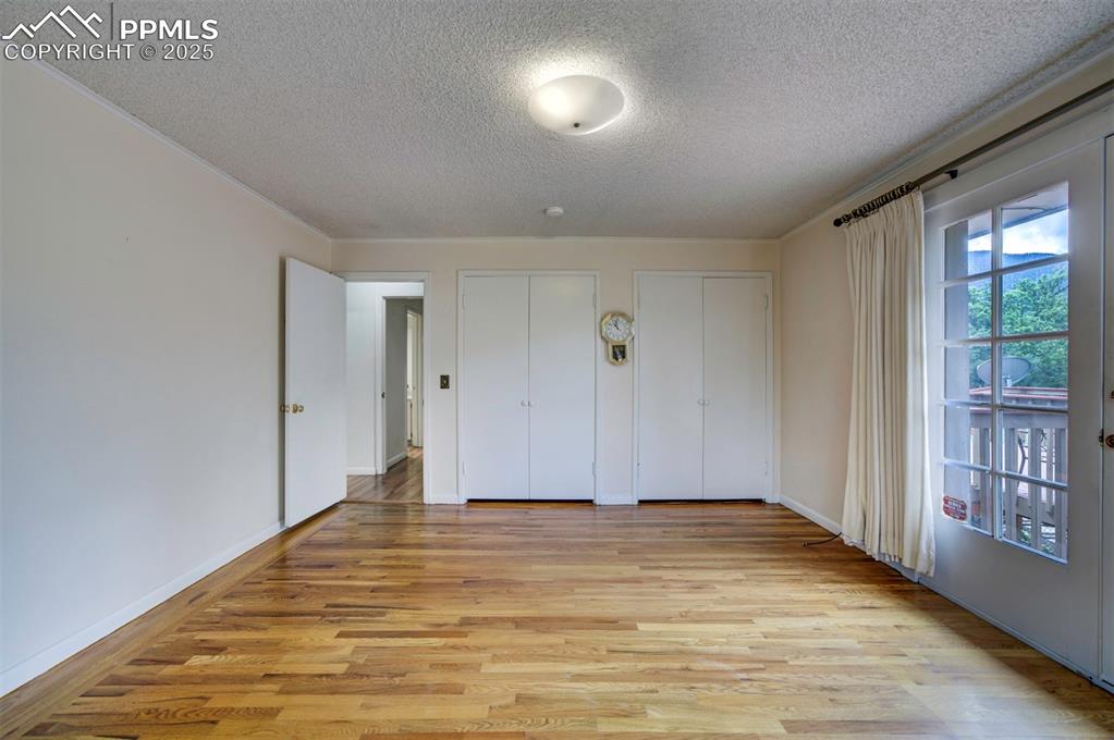 Image 28 of 49: Unfurnished bedroom with a textured ceiling, two closets, light wood-style