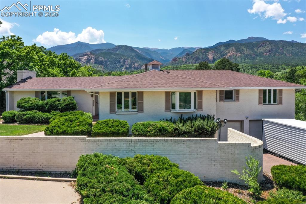 Image 3 of 49: Ranch-style house featuring a mountain view, a garage, and a chimney