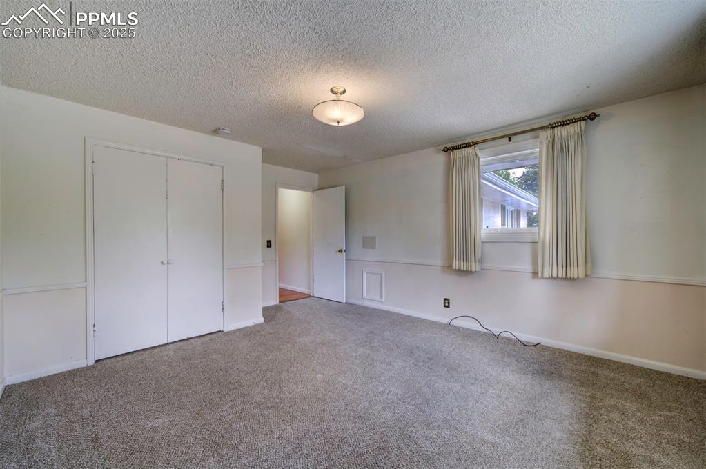 Image 33 of 49: Unfurnished bedroom with carpet, a textured ceiling, and a closet