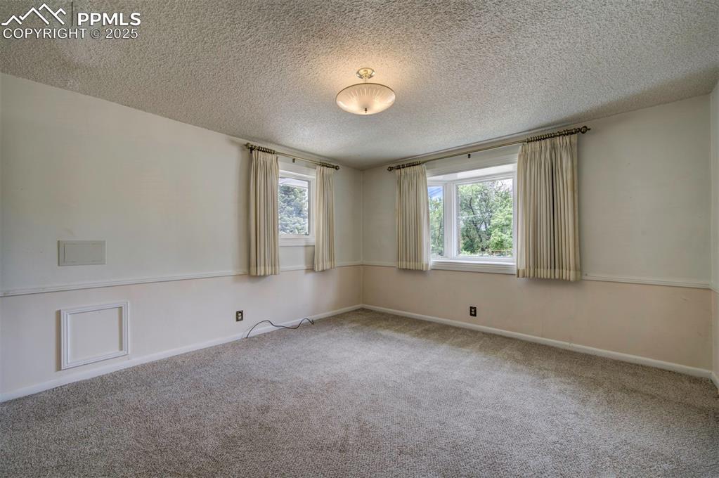Image 34 of 49: Spare room featuring carpet floors, a textured ceiling, and baseboards