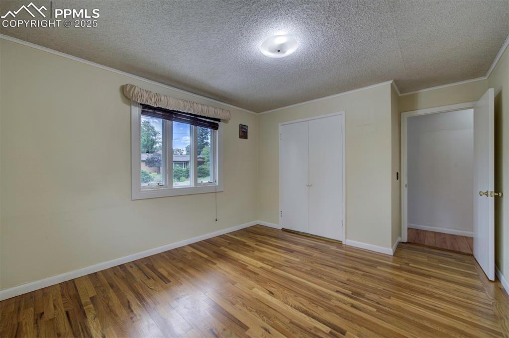 Image 36 of 49: Unfurnished bedroom featuring a textured ceiling, wood finished floors, orn