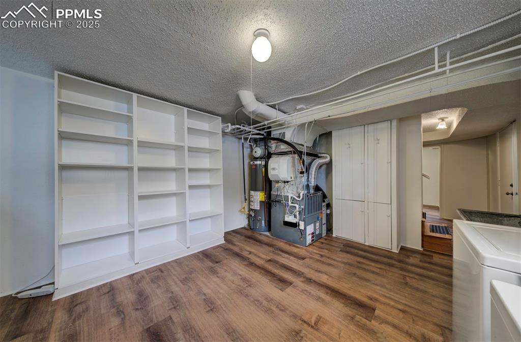 Image 39 of 49: Finished basement featuring gas water heater, dark wood finished floors, a