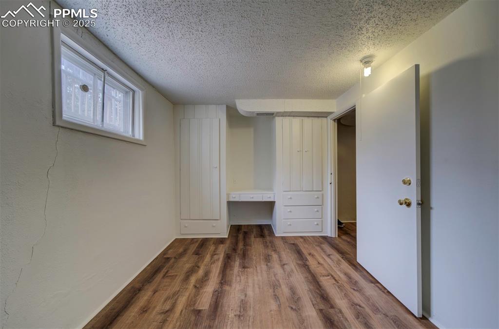 Image 40 of 49: Unfurnished bedroom featuring wood finished floors, a textured ceiling, and