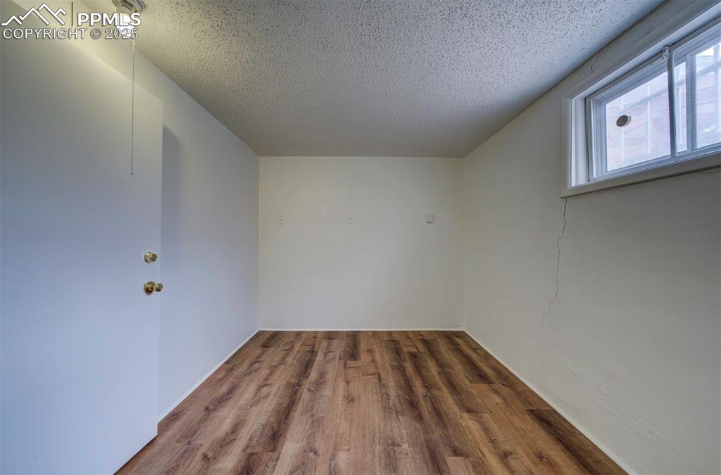 Image 42 of 49: Bonus room featuring a textured ceiling and wood finished floors