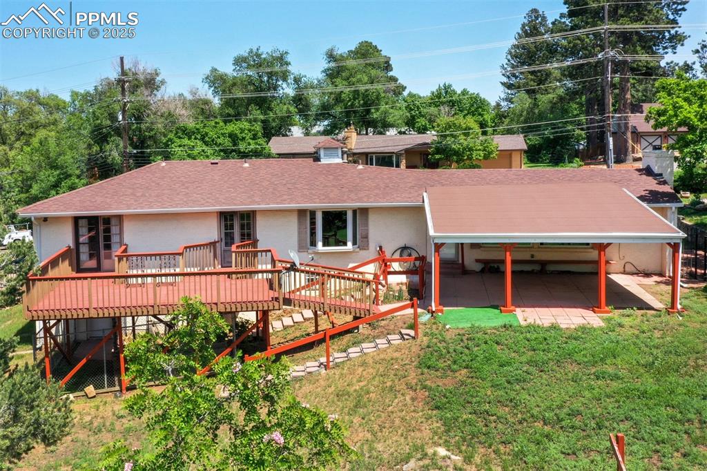 Image 46 of 49: Back of house featuring roof with shingles, a wooden deck, a yard, and stuc