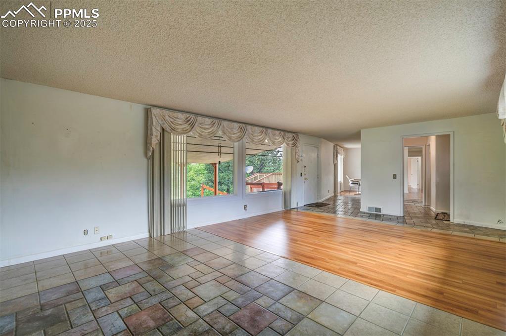 Image 5 of 49: Unfurnished living room with a textured ceiling, baseboards, and wood finis