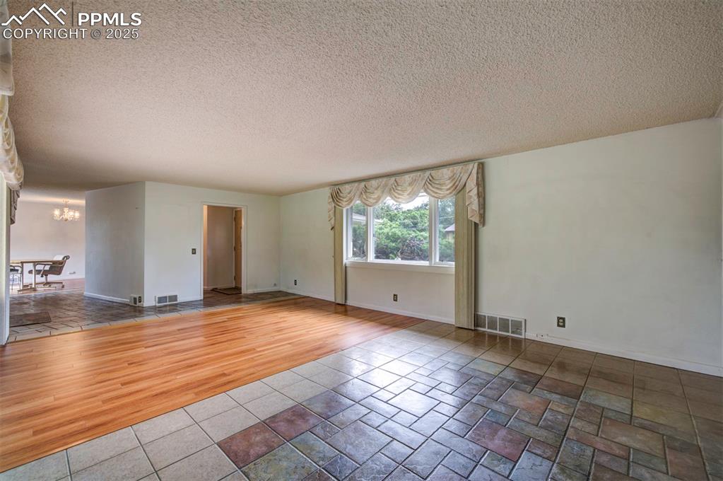 Image 6 of 49: Empty room featuring a chandelier, a textured ceiling, wood finished floors