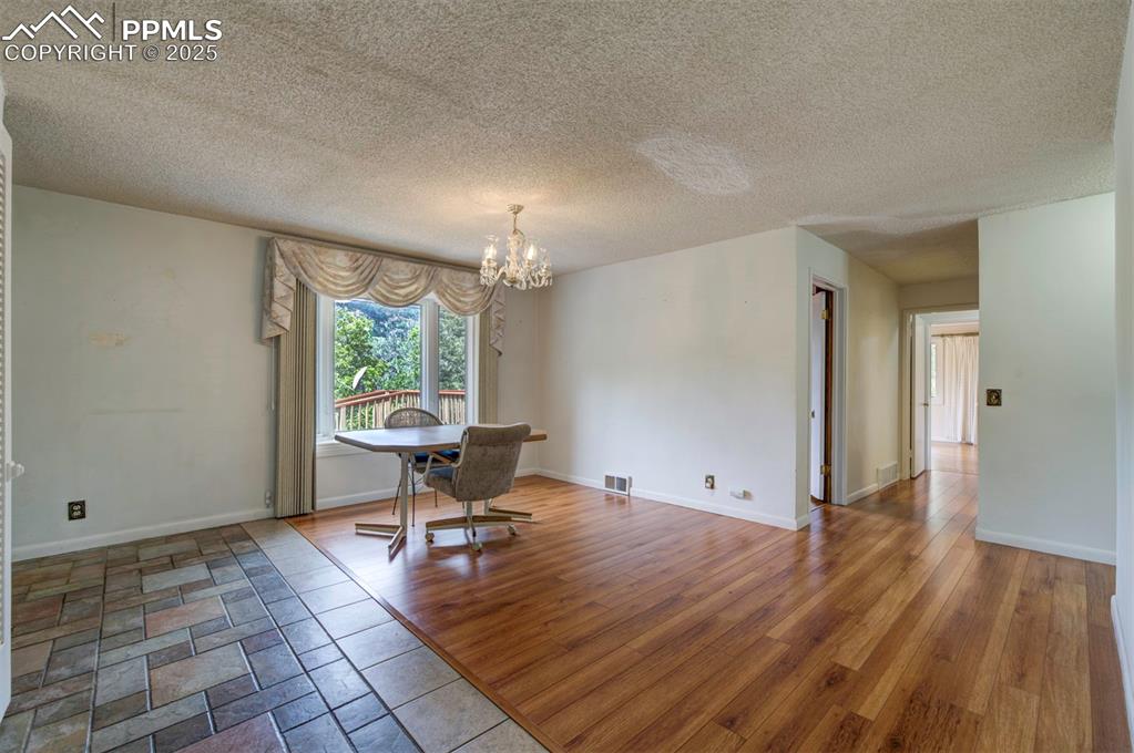 Image 7 of 49: Unfurnished dining area featuring a chandelier, a textured ceiling, wood fi