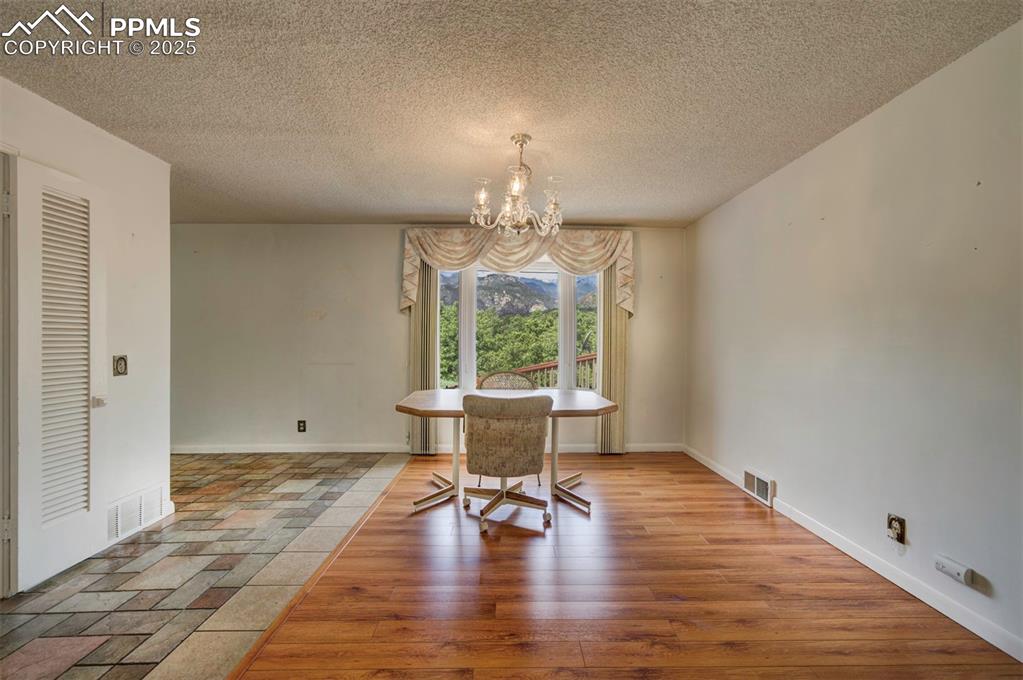 Image 8 of 49: Dining room featuring a chandelier, a textured ceiling, and baseboards