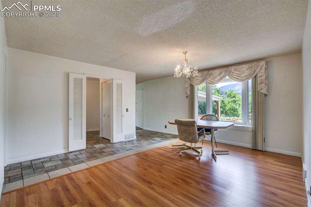 Image 9 of 49: Dining room with wood finished floors, a chandelier, baseboards, and a text