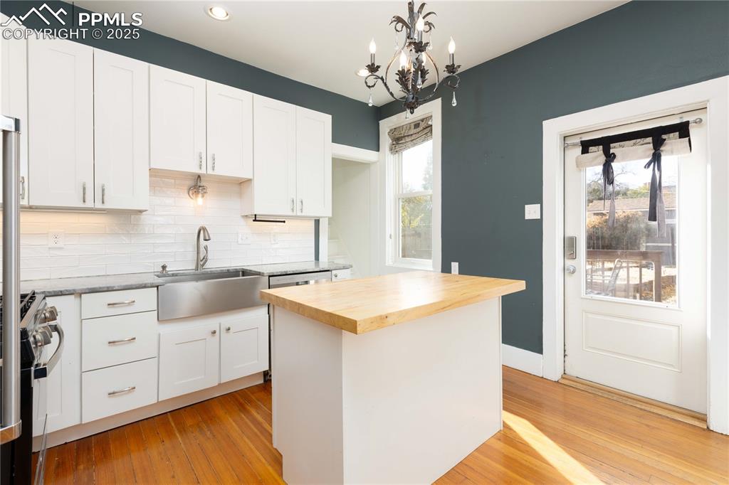 Image 12 of 31: Kitchen featuring butcher block countertops, white cabinetry, backsplash, l