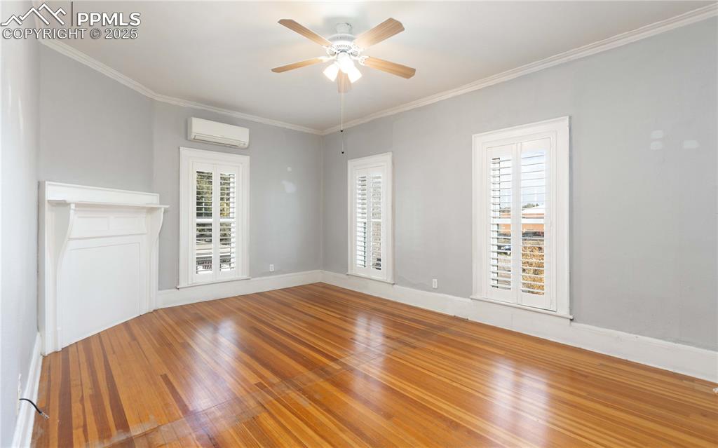 Image 14 of 31: Empty room with wood finished floors, crown molding, ceiling fan, and a wal