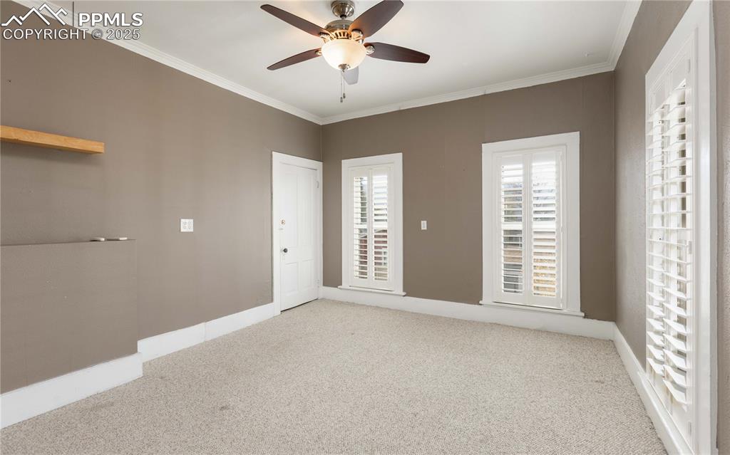 Image 18 of 31: Spare room featuring crown molding, carpet, and a ceiling fan