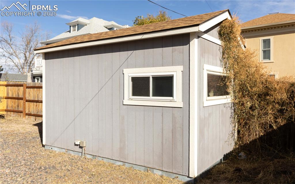 Image 23 of 31: View of side of home with an outdoor structure and roof with shingles