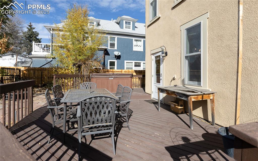 Image 26 of 31: Wooden deck with a hot tub and outdoor dining area