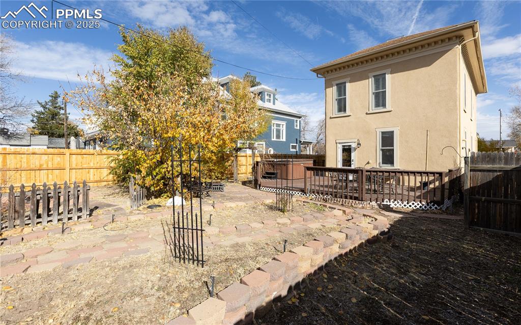 Image 31 of 31: Rear view of house with stucco siding, a fenced backyard, and a wooden deck