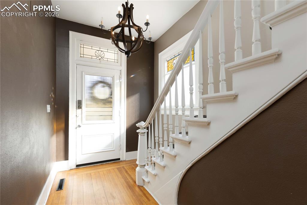Image 5 of 31: Entrance foyer with light wood-style flooring, a chandelier, and stairs