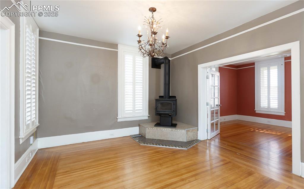 Image 6 of 31: Unfurnished living room featuring wood finished floors and a wood stove
