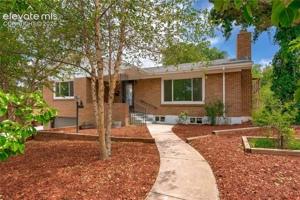 Image 1 of 38: Brick exterior featuring a prominent chimney, a curved concrete walkway, an