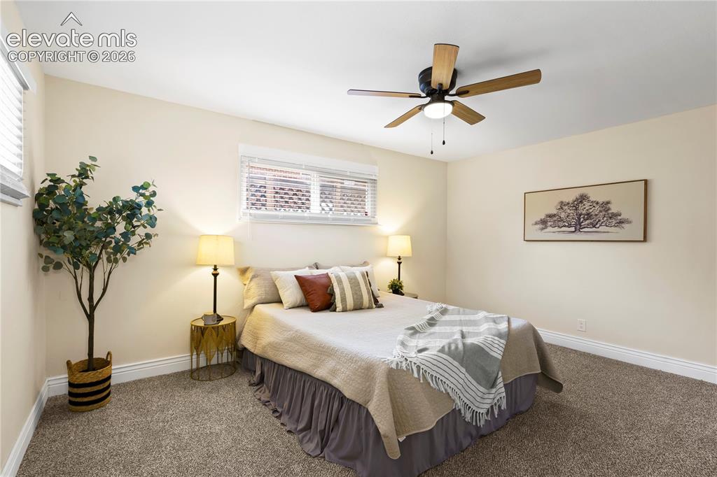 Image 11 of 36: Carpeted room featuring a ceiling fan with integrated lighting, multiple wi