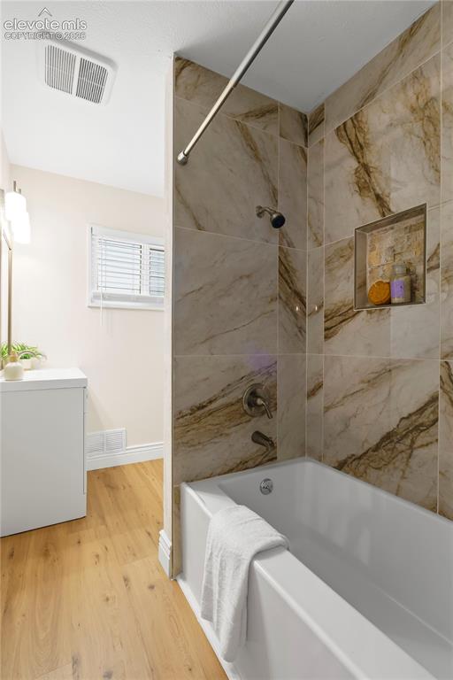 Image 14 of 36: Bathtub with a shower featuring large format wall tiles in a marble-look fi
