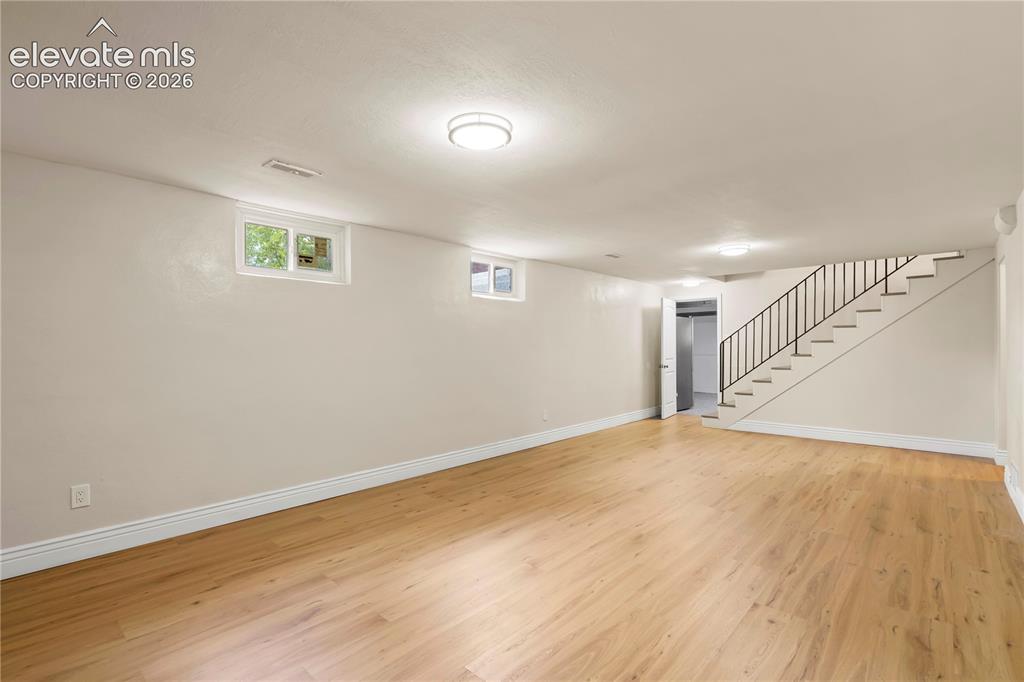Image 16 of 36: Spacious room featuring wood-finish flooring, light neutral wall tones, mul