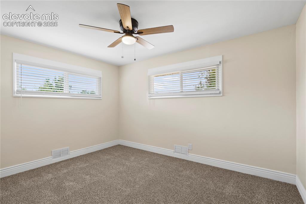 Image 18 of 36: Room featuring two windows with horizontal blinds, a ceiling fan with light