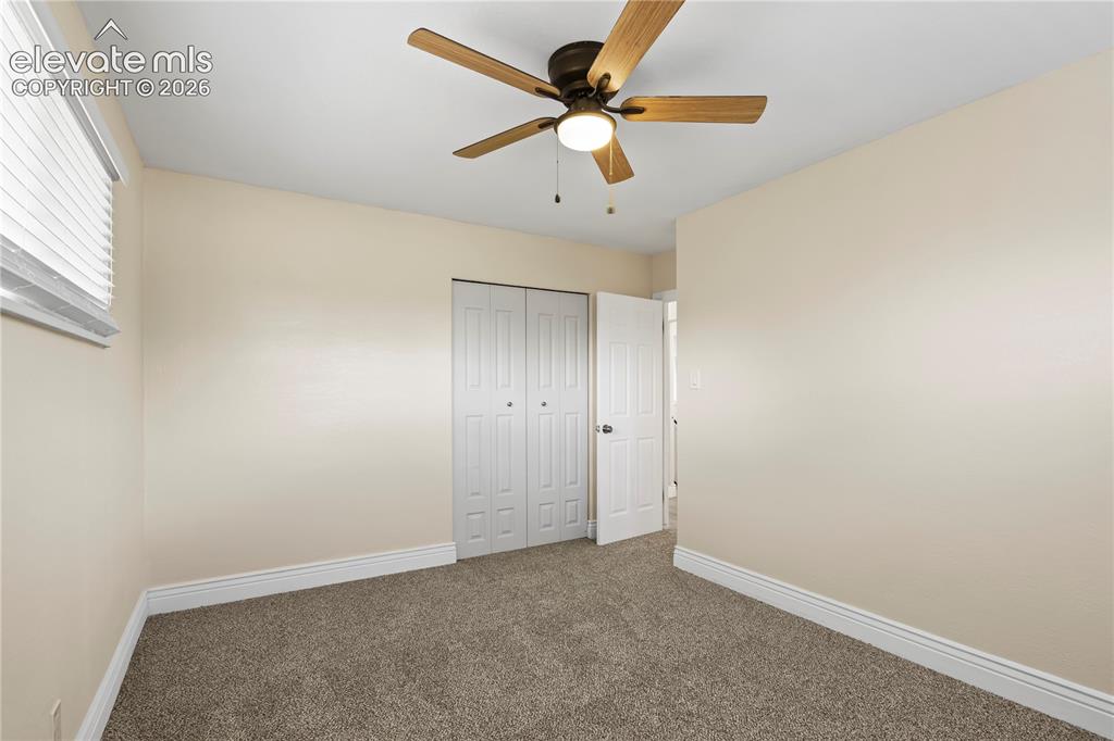 Image 19 of 36: Neutral-toned room featuring a ceiling fan with wood-finish blades and inte