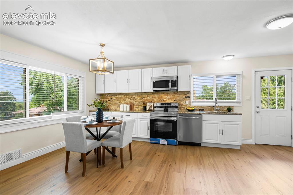 Image 2 of 36: Open-concept kitchen and dining area featuring wood-finish flooring, white
