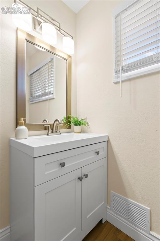 Image 21 of 36: Contemporary vanity featuring a white countertop, integrated sink, brushed