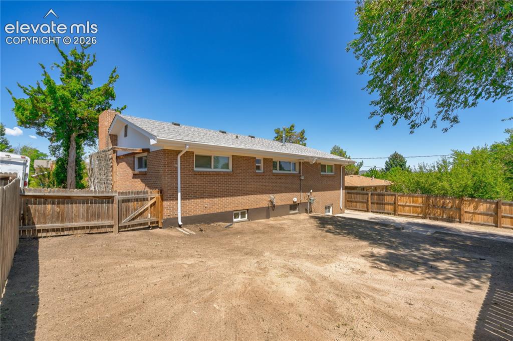 Image 24 of 36: Spacious outdoor area featuring a brick exterior, perimeter wood fencing, a